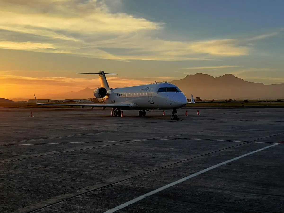 Light business jet on a ramp at sunset with mountains behind