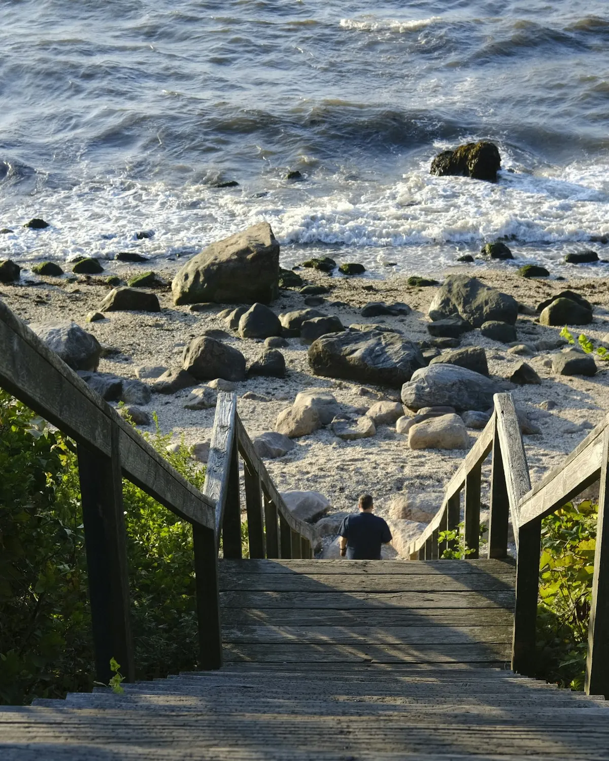 Wooden steps leading down to a rocky beach on the New England coast